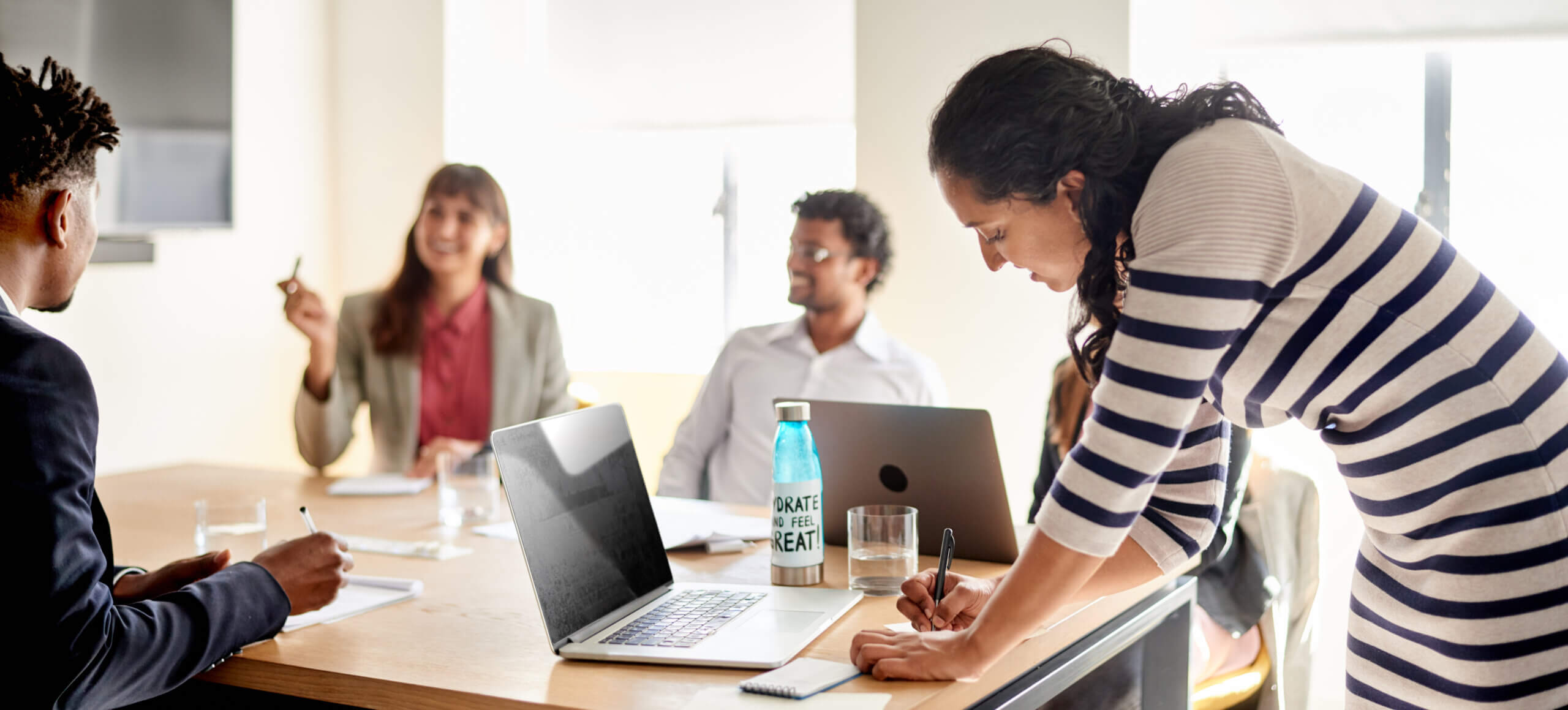 Young businesswoman taking notes during a meeting with staff in an office